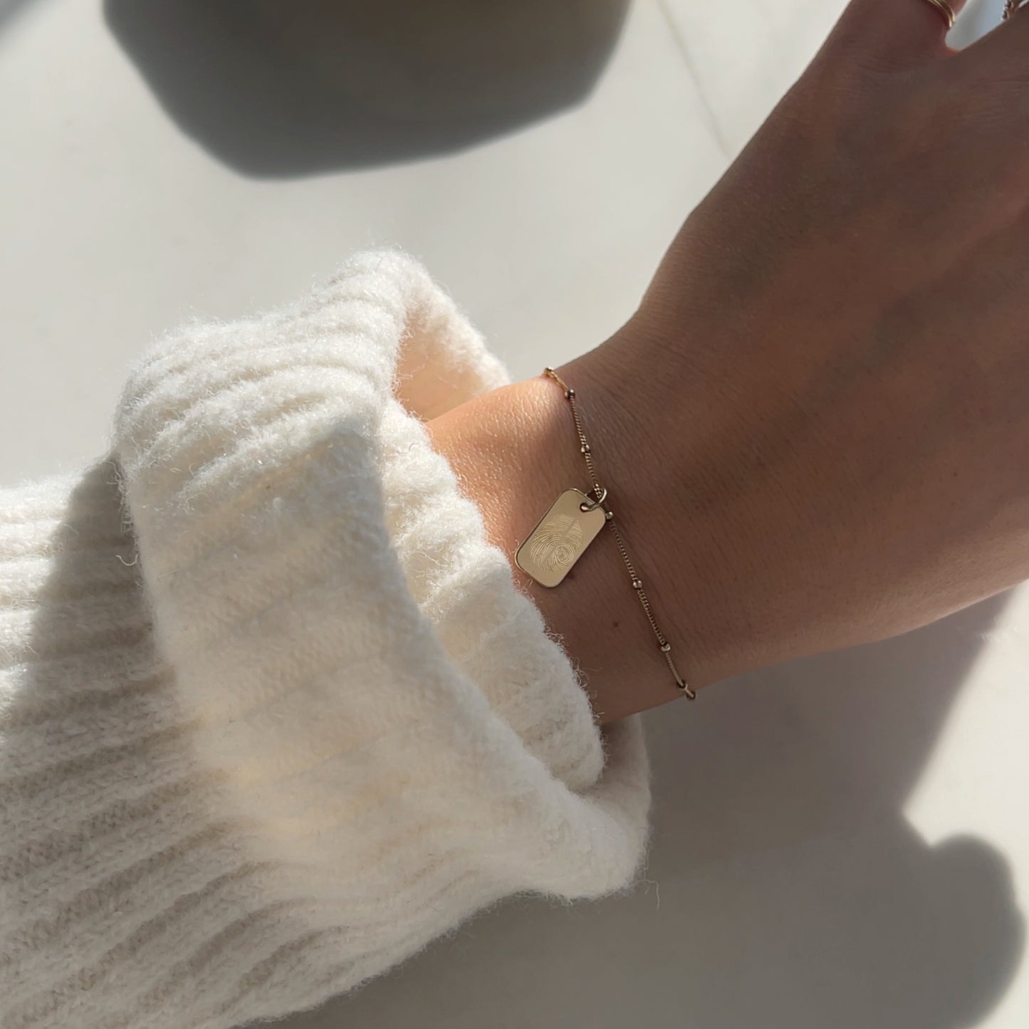 Woman wearing a 10K solid gold Actual Two Fingerprint Personalized Rectangle Pendant on chain bracelet