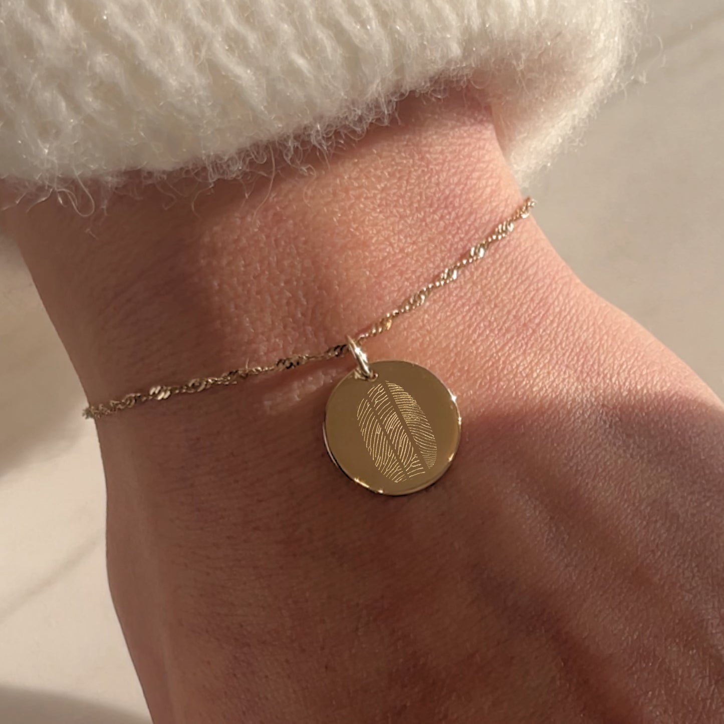 Woman wearing a solid gold bracelet with 3 fingerprints engraved