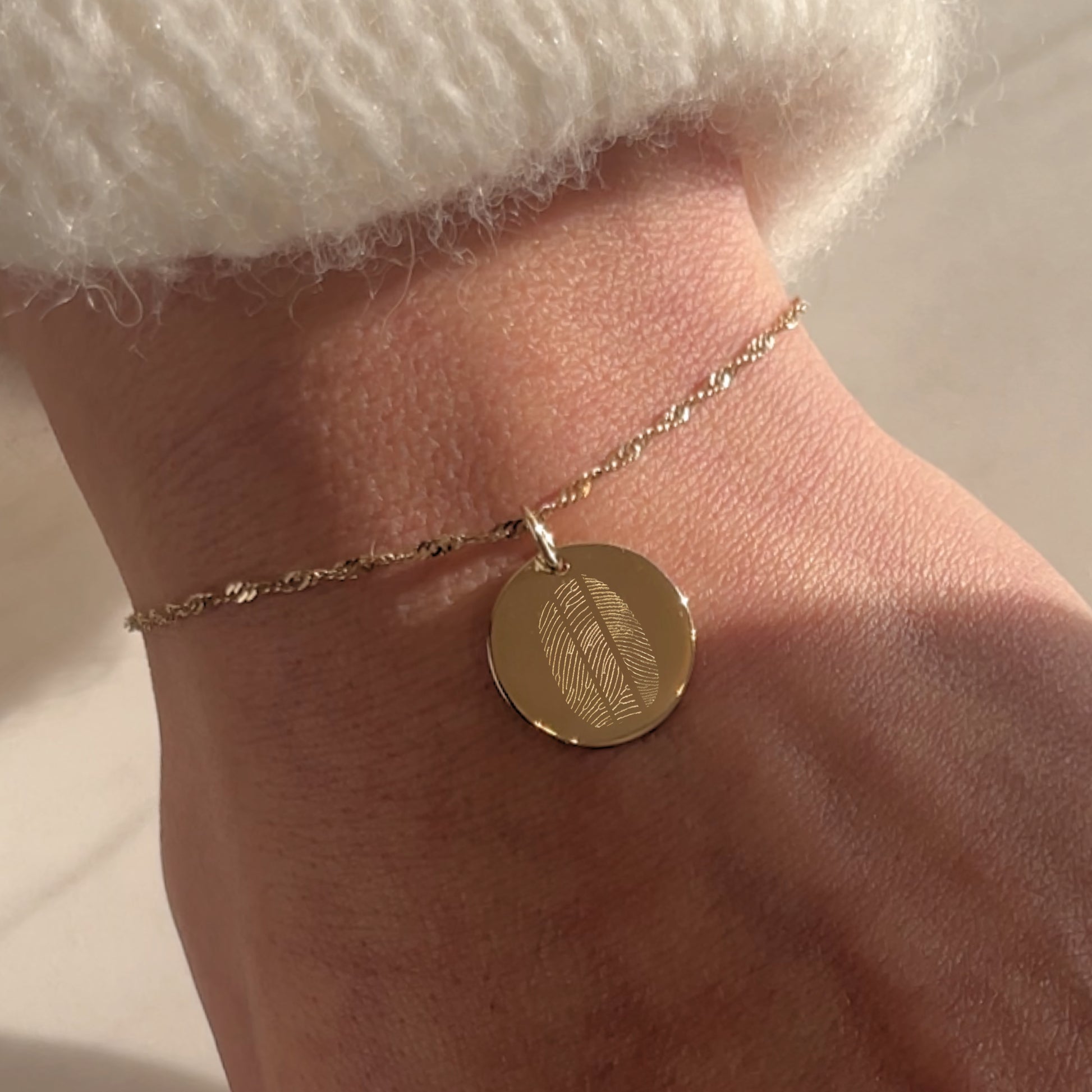 Woman wearing a solid gold bracelet with 3 fingerprints engraved
