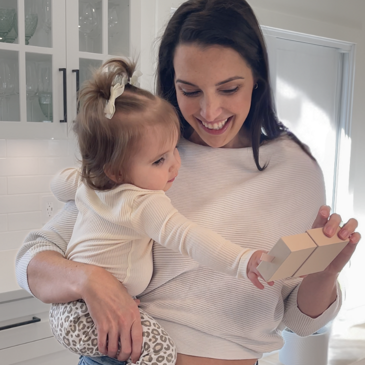 Woman holding a baby unwrapping a fingerprint jewelry gift